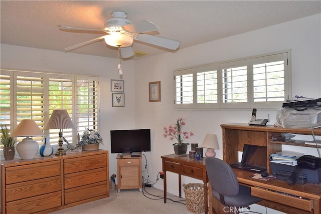 office area featuring a textured ceiling, ceiling fan, a healthy amount of sunlight, and light carpet