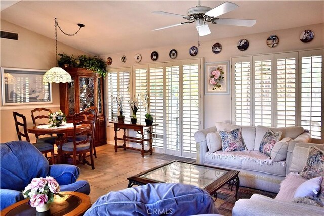 living room with a wealth of natural light, light tile patterned floors, lofted ceiling, and ceiling fan