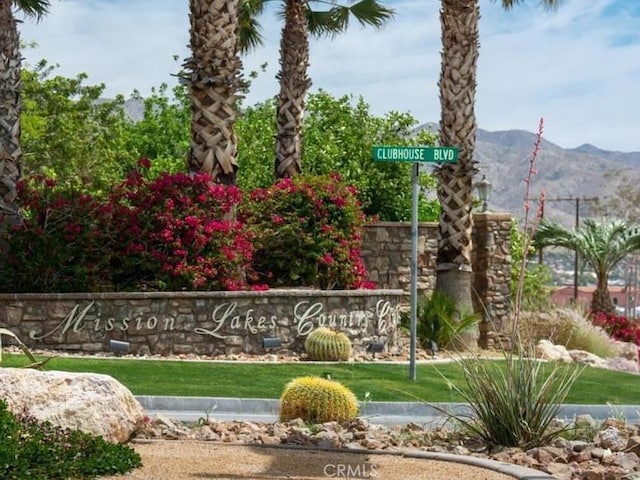 community sign with a mountain view and a yard