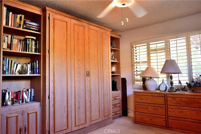 interior space featuring ceiling fan, light colored carpet, and a textured ceiling