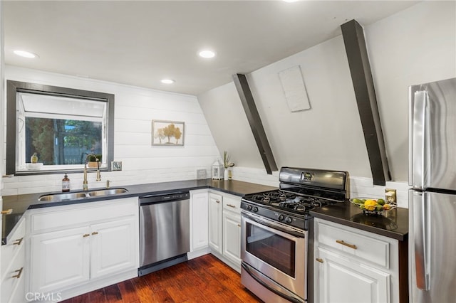 kitchen with appliances with stainless steel finishes, white cabinetry, dark wood-type flooring, beam ceiling, and sink