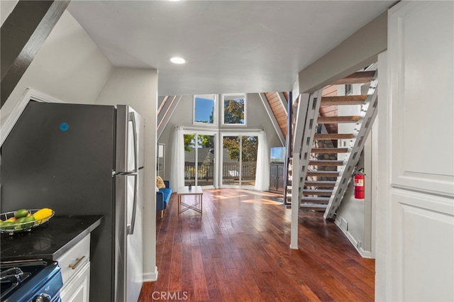 kitchen with white cabinets, lofted ceiling, stainless steel refrigerator, dark hardwood / wood-style flooring, and black range with electric cooktop