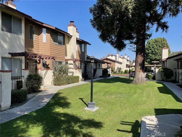 view of community featuring a yard and a pergola