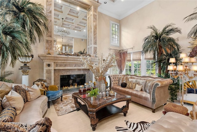 living room featuring light wood-type flooring, a high end fireplace, coffered ceiling, crown molding, and a towering ceiling