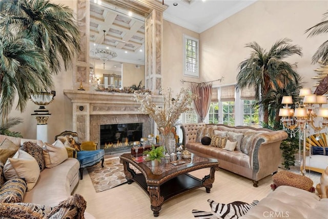 living room featuring coffered ceiling, a towering ceiling, a high end fireplace, and ornamental molding