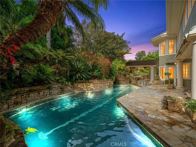 pool at dusk with a patio area