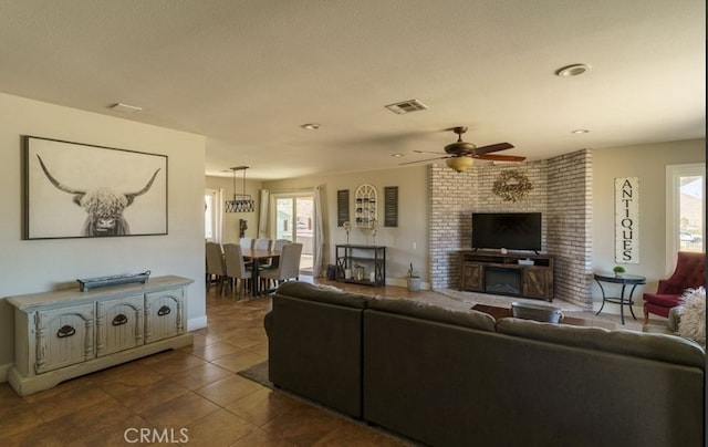 living room with ceiling fan, dark tile patterned floors, and a large fireplace