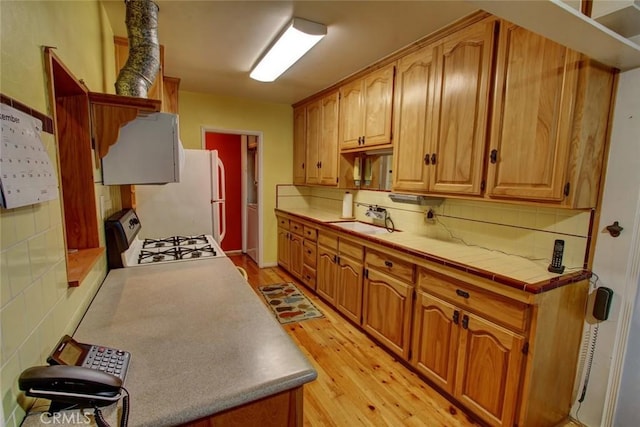 kitchen featuring tasteful backsplash, sink, tile counters, white appliances, and light hardwood / wood-style flooring