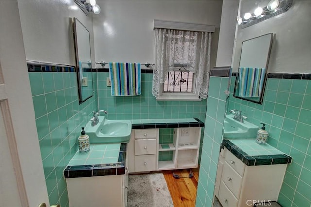 bathroom with sink, hardwood / wood-style floors, and tile walls