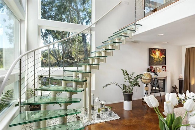 stairs featuring a towering ceiling, concrete floors, and plenty of natural light