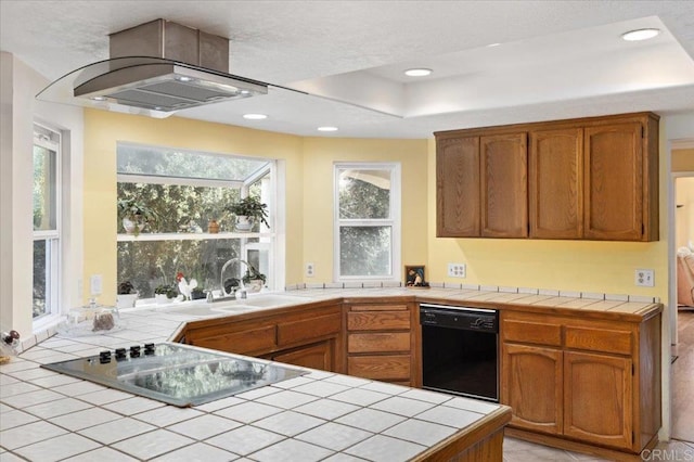 kitchen featuring sink, kitchen peninsula, island range hood, black appliances, and tile counters