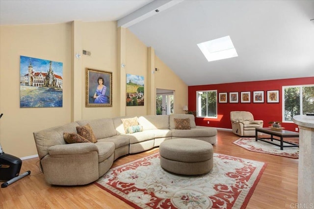 living room featuring wood-type flooring, beam ceiling, a skylight, and a healthy amount of sunlight