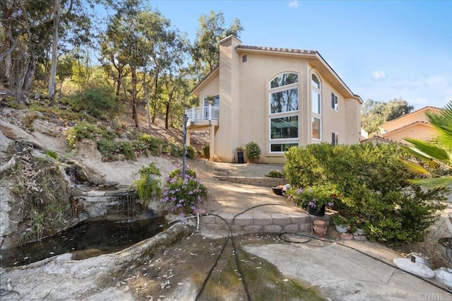 rear view of property featuring a balcony and a patio