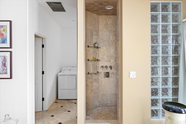 bathroom featuring a tile shower, washer / clothes dryer, and tile patterned floors