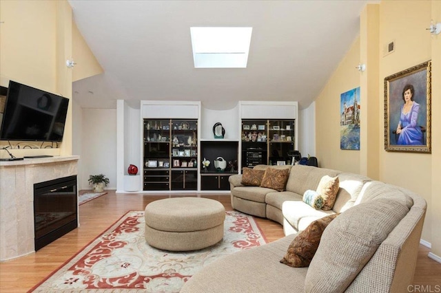 living room featuring vaulted ceiling with skylight and hardwood / wood-style flooring