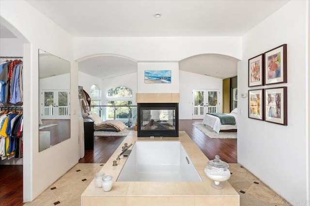 interior space featuring lofted ceiling, a bathing tub, and hardwood / wood-style floors