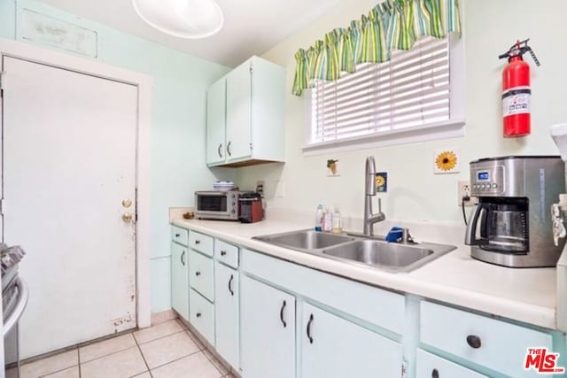 kitchen with white cabinetry, stainless steel range oven, light tile patterned floors, and sink