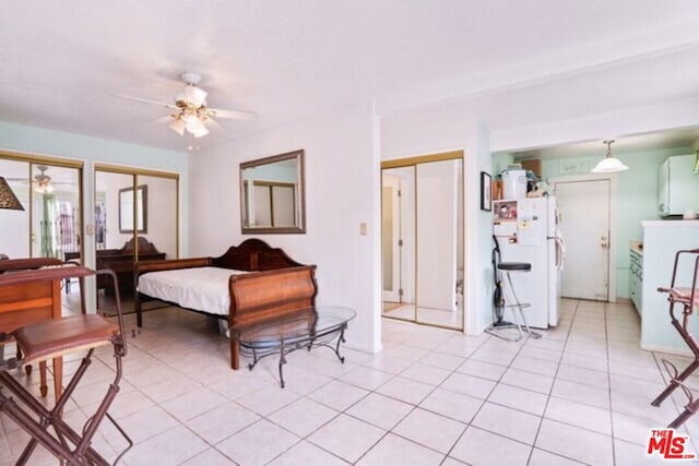 tiled bedroom with ceiling fan, multiple closets, and white refrigerator