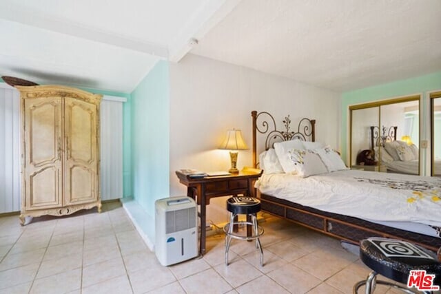 tiled bedroom with lofted ceiling with beams and a closet