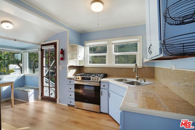 kitchen with light hardwood / wood-style floors, sink, stainless steel range with gas stovetop, and white cabinets