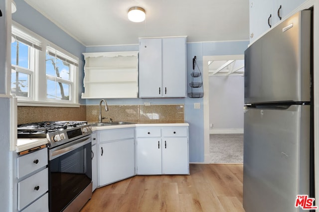 kitchen with light hardwood / wood-style floors, sink, white cabinets, backsplash, and appliances with stainless steel finishes