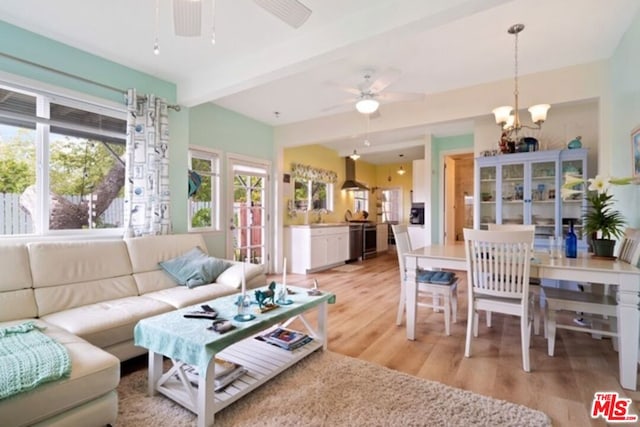 living room with ceiling fan with notable chandelier, beamed ceiling, light hardwood / wood-style flooring, and sink