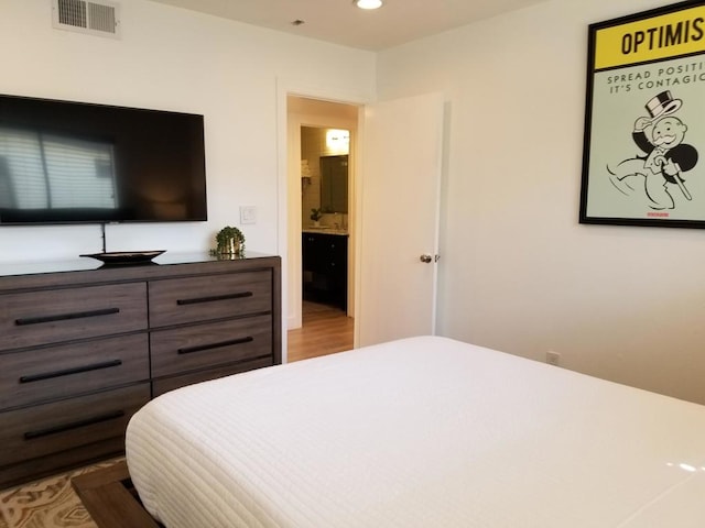 bedroom with light wood-type flooring and ensuite bathroom