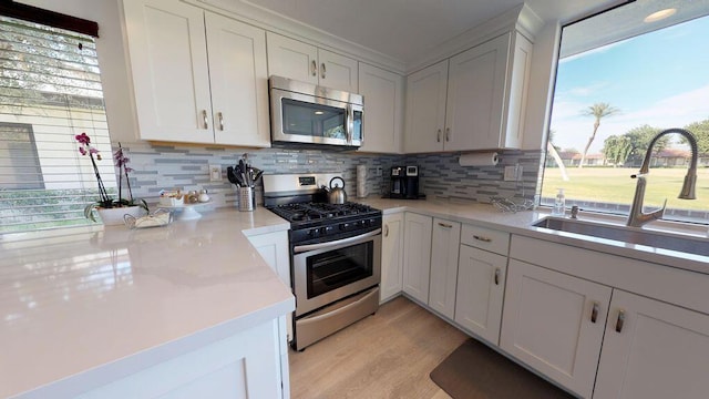 kitchen with appliances with stainless steel finishes, white cabinetry, sink, and plenty of natural light