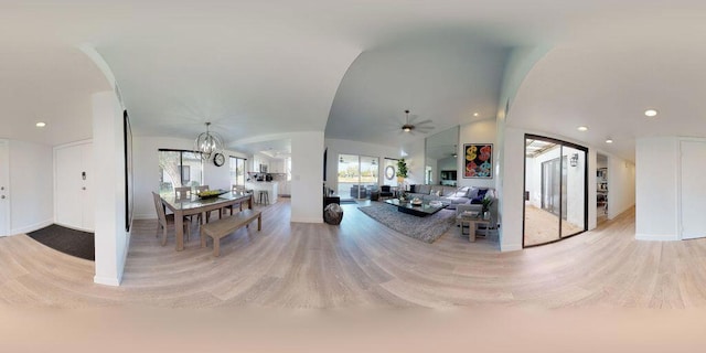 living room with ceiling fan with notable chandelier, light wood-type flooring, and lofted ceiling