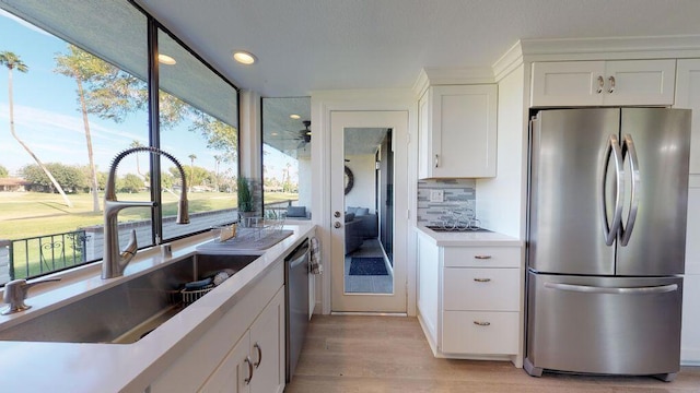 kitchen featuring decorative backsplash, light hardwood / wood-style floors, white cabinetry, stainless steel appliances, and sink