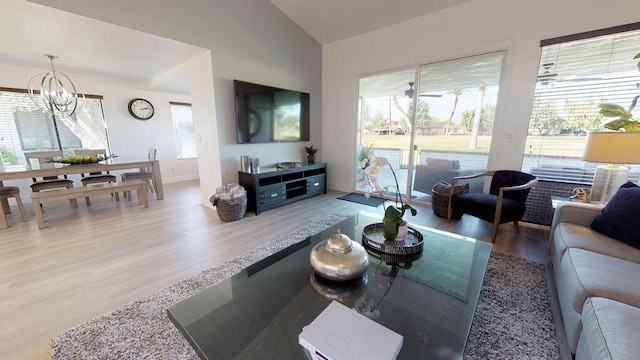 living room featuring an inviting chandelier, lofted ceiling, and hardwood / wood-style flooring