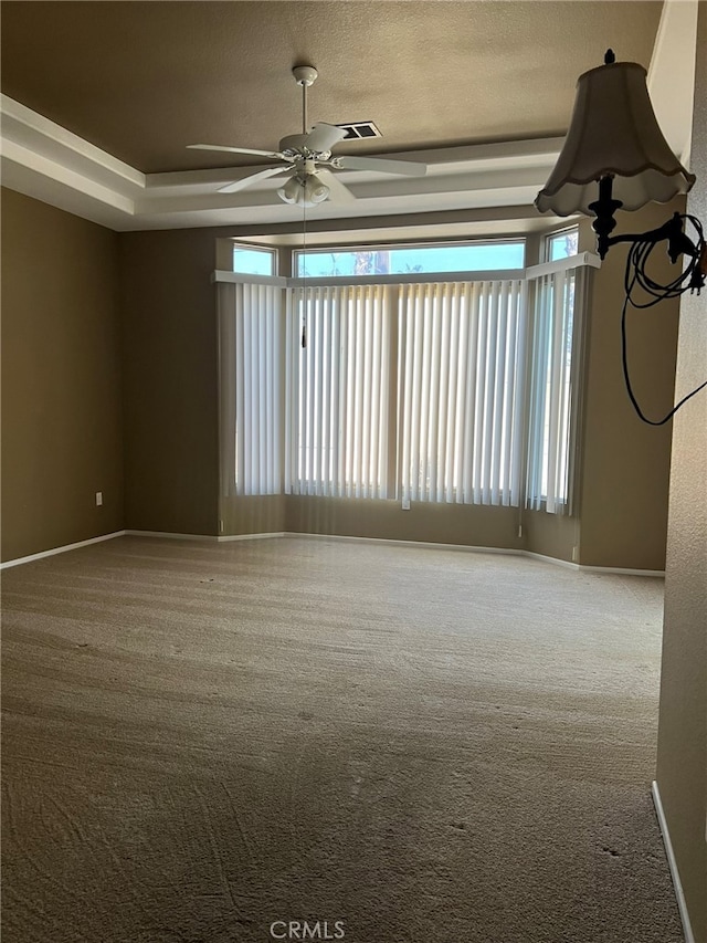 unfurnished room with ceiling fan, a raised ceiling, carpet floors, and a textured ceiling