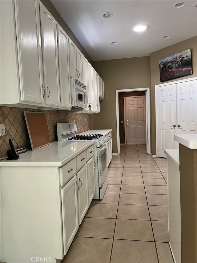 kitchen featuring white appliances, white cabinetry, light tile patterned floors, and tasteful backsplash