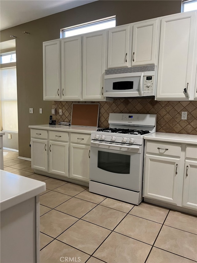 kitchen featuring decorative backsplash, white appliances, and a wealth of natural light