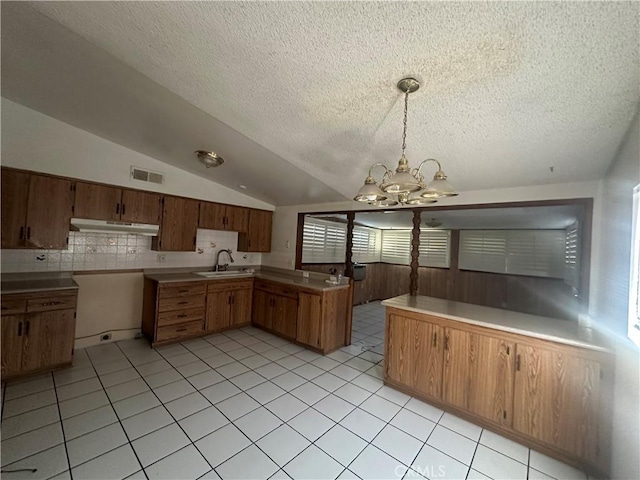 kitchen with lofted ceiling, sink, a chandelier, hanging light fixtures, and kitchen peninsula