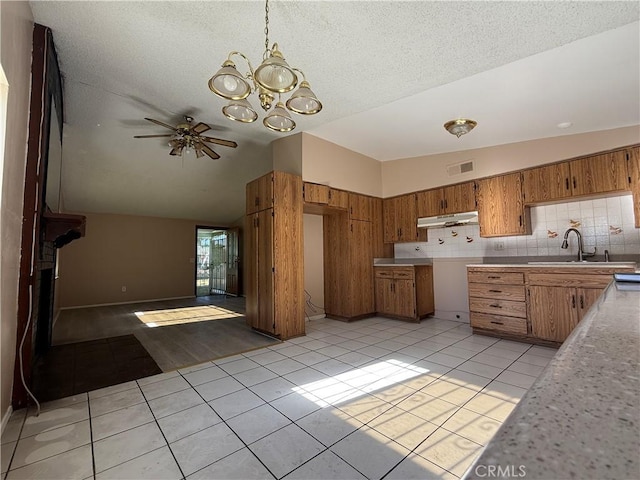 kitchen with ceiling fan with notable chandelier, lofted ceiling, sink, decorative backsplash, and light tile patterned floors