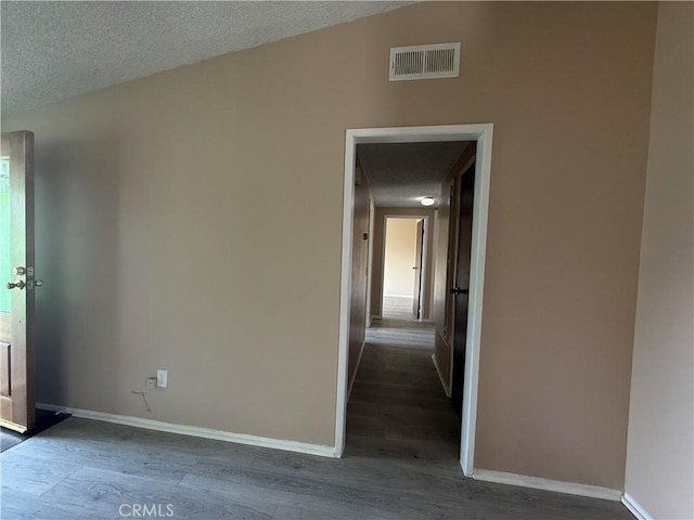 empty room with a textured ceiling and dark hardwood / wood-style flooring