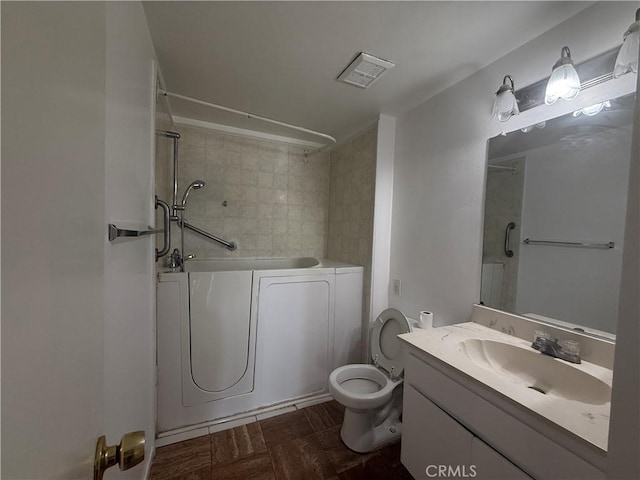 full bathroom with toilet, tiled shower / bath, washer and dryer, parquet floors, and vanity