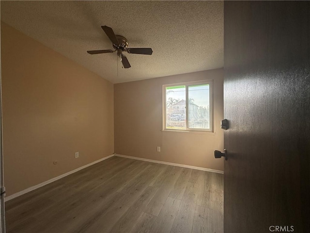 unfurnished room featuring ceiling fan, wood-type flooring, vaulted ceiling, and a textured ceiling