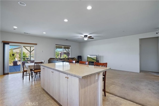 kitchen featuring a breakfast bar, a kitchen island, light carpet, and a wealth of natural light