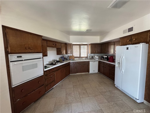 kitchen featuring dark brown cabinetry, sink, and white appliances