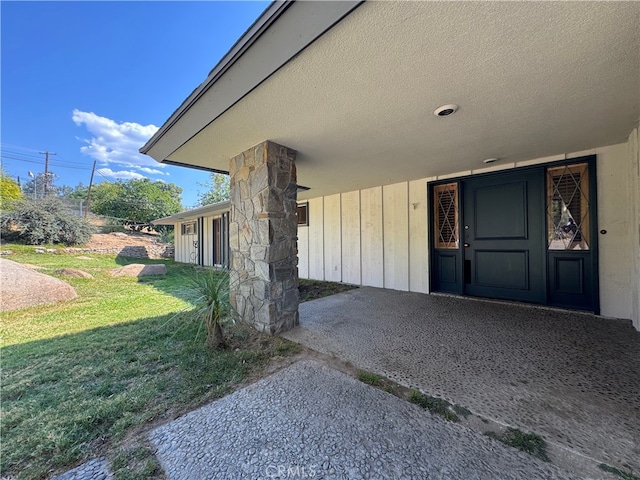 view of exterior entry with a yard and a patio