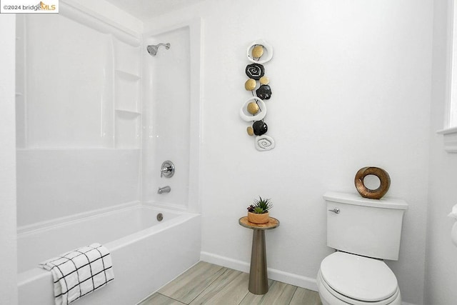 bathroom featuring washtub / shower combination, hardwood / wood-style floors, and toilet