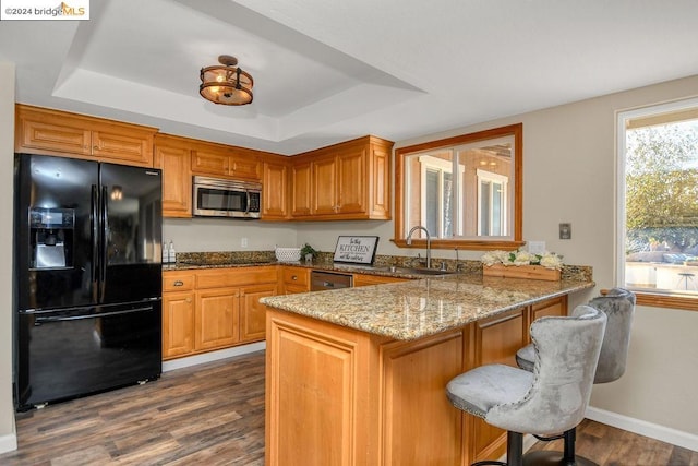 kitchen with black appliances, kitchen peninsula, a tray ceiling, and sink