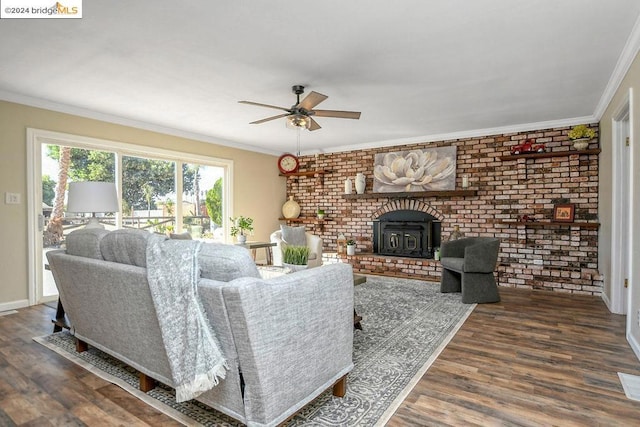 living room featuring brick wall, crown molding, dark wood-type flooring, and a wood stove