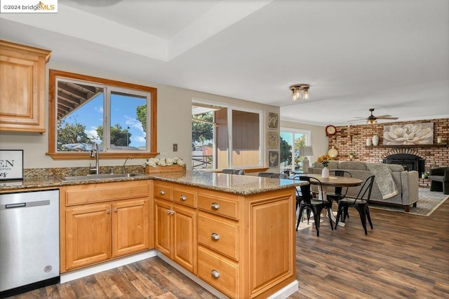 kitchen featuring dishwasher, dark wood-type flooring, sink, kitchen peninsula, and a brick fireplace