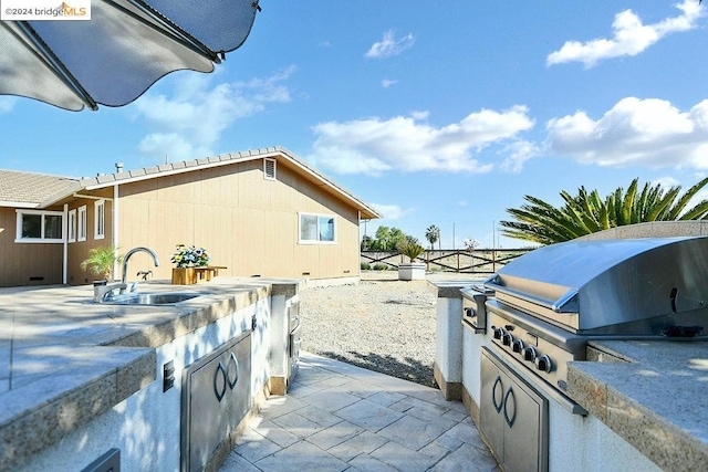 view of patio featuring exterior kitchen, sink, and a grill