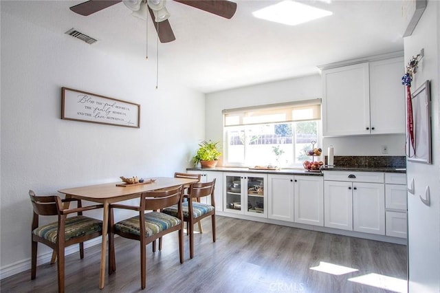 kitchen with white cabinetry, ceiling fan, dark stone countertops, and light wood-type flooring