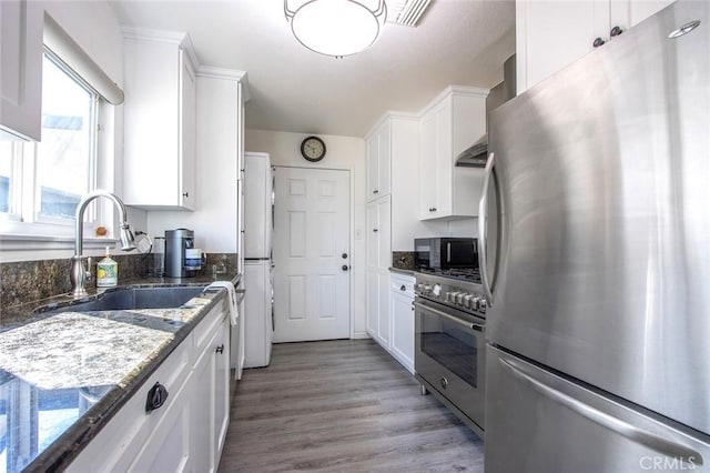 kitchen featuring sink, dark stone counters, white cabinets, and appliances with stainless steel finishes