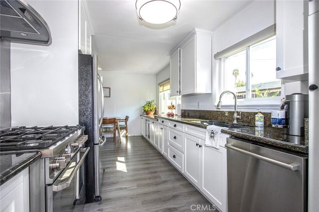 kitchen featuring white cabinetry, appliances with stainless steel finishes, and dark stone countertops